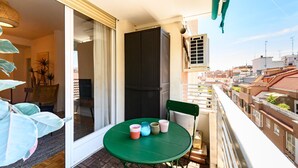 Ein Balkon mit einem grünen Tisch, einem Stuhl und Blick auf die Stadt.