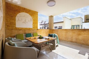 A balcony with wicker furniture, a table with a fruit bowl and book, and a mural on the wall. - Stay Inn on Buzand 13 (Yerevan)