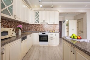 A kitchen with white cabinets, a tiled backsplash, a built-in oven, and a granite countertop. - Stay Inn on Buzand 13 (Yerevan)