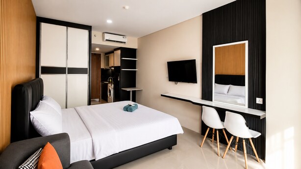 A modern hotel room with a bed, a desk, a TV, and a seating area. - SleepRest @ NTC (Batam)