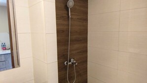 A shower with a handheld showerhead and a wall-mounted faucet. - SleepRest @ NTC (Batam)
