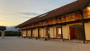 A building with a tiled roof, multiple windows, and a gravel courtyard. - Agriturismo Modolo (Belluno)