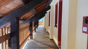 A wooden corridor with a sloped ceiling, wooden beams, and a patterned floor. - Agriturismo Modolo (Belluno)
