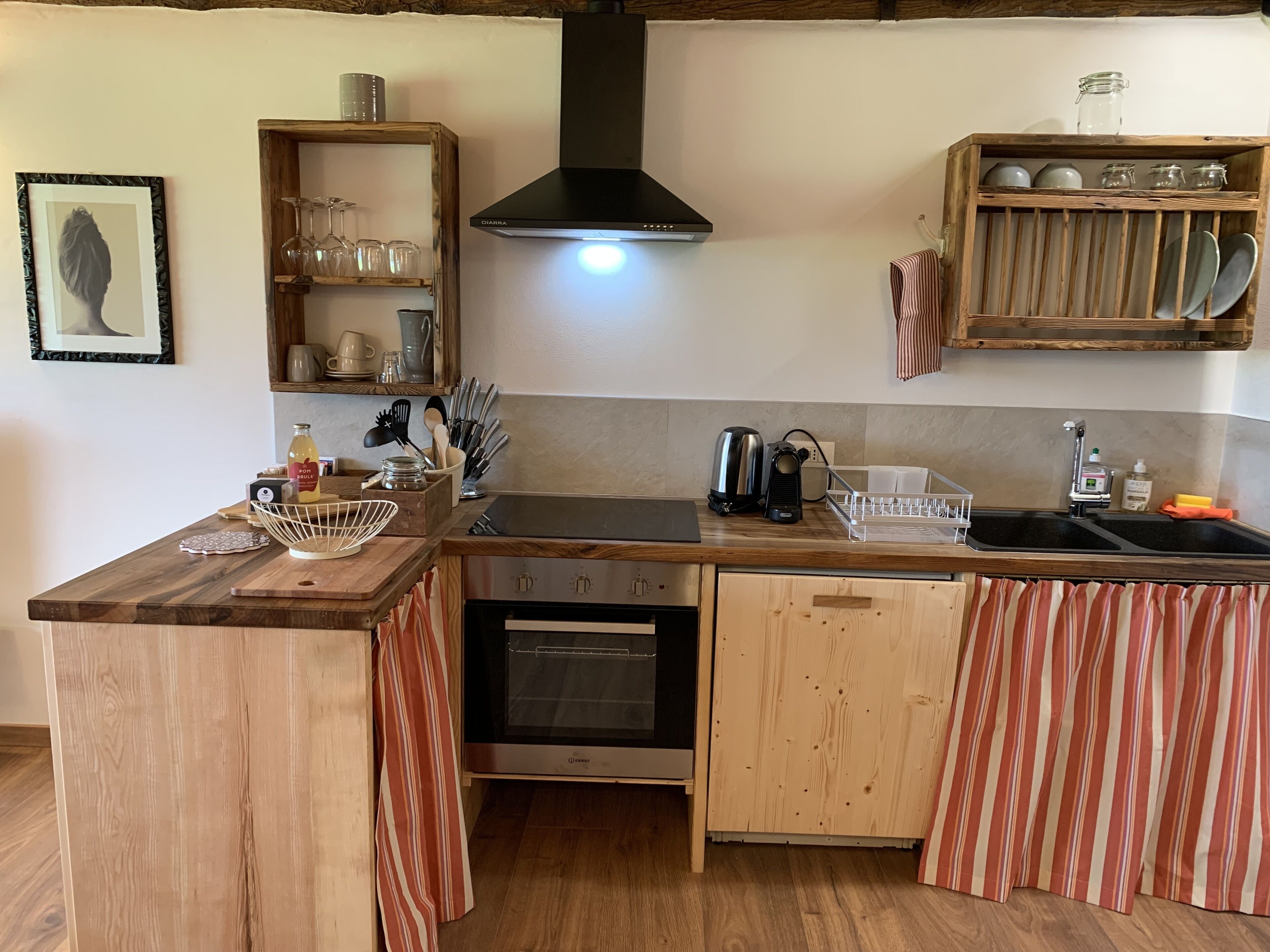 Una cocina compacta con encimeras de madera, horno empotrado, cafetera y un lavamanos.