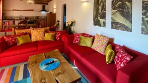 A cozy living room with a red sectional sofa, a wooden coffee table, and a star-shaped hanging light. - Agriturismo Modolo (Belluno)