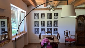A cozy living room with a red sofa, a dining table with chairs, a star ceiling light, and a wall of framed pictures. - Agriturismo Modolo (Belluno)