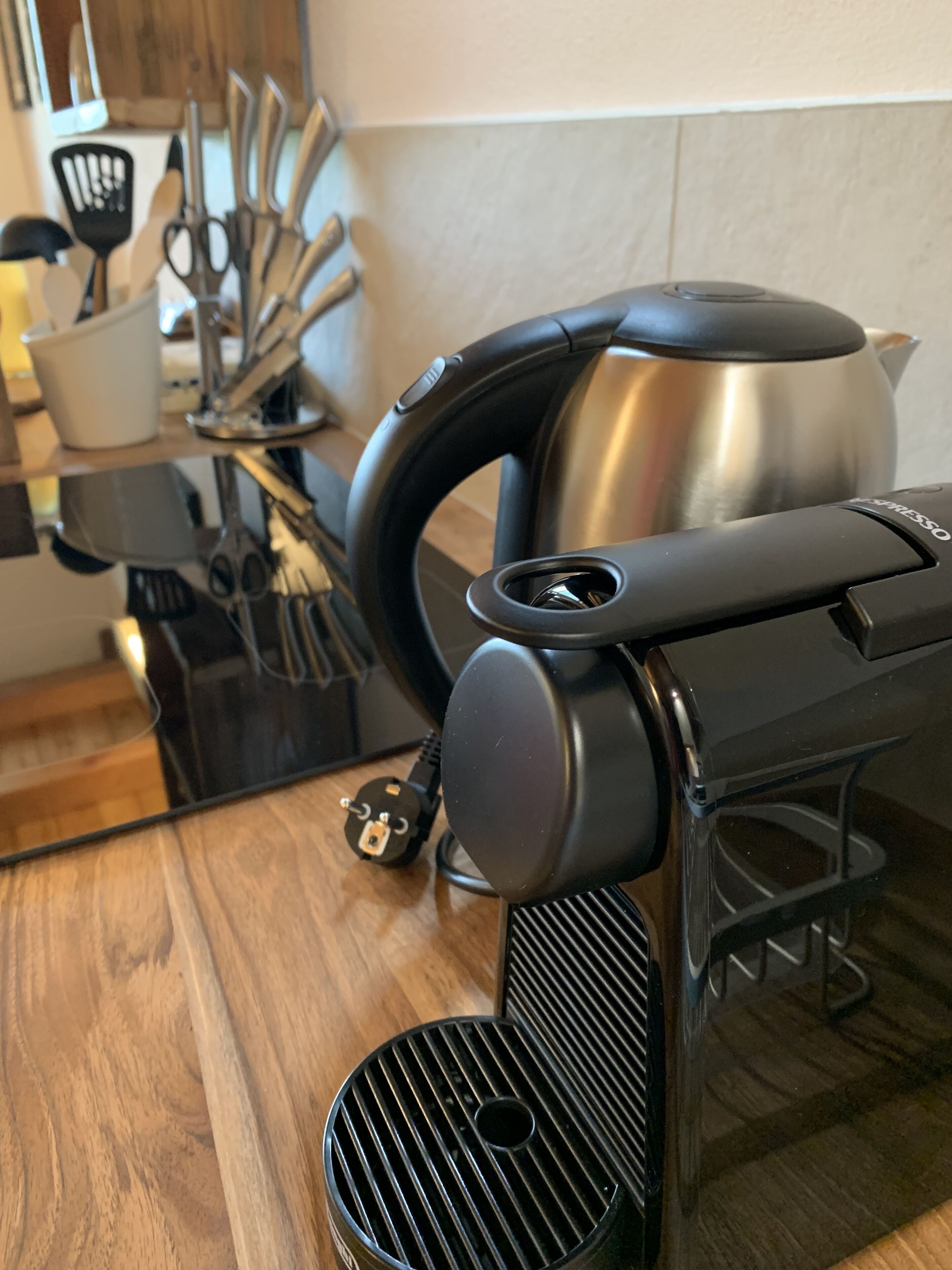 A kitchen with a coffee machine, a kettle, and various utensils.