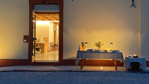 A building with a sign reading "Agriturismo Modolo" and an open door leading to an interior space with a table set for dining. - Agriturismo Modolo (Belluno)