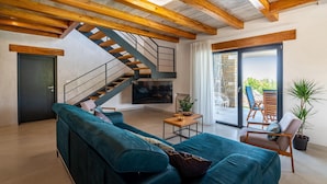 Un salon moderne avec un plafond en bois, un canapé bleu, une petite table et un escalier.