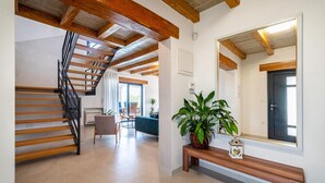 Un vaste espace de vie agrémenté d’un escalier en bois, d’un grand miroir et d’une plante en pot.
