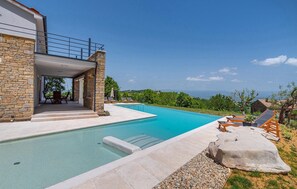 A modern poolside area with a stone facade, a covered seating area, and a clear view of the landscape. - Gorgeous home in Pazin (Pazin)