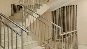 A staircase with metal railings and beige walls, leading to an upper floor. - Breakfort Hotel and Suites (Uyo)