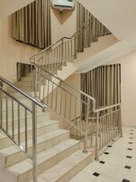 Una escalera con barandillas metálicas y paredes color beige, que lleva a un piso superior.