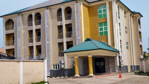A multi-story building with a central entrance, large windows, and a tiled roof. - Breakfort Hotel and Suites (Uyo)