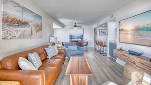 Un salon moderne avec un canapé en cuir, une table basse en bois et des œuvres d’art accrochées aux murs.