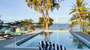 Un espace piscine avec des chaises longues et vue sur la mer.