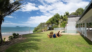 A house with a view of the ocean, a grassy yard, and a pool area.