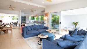 A modern living room with a sofa, coffee table, and a dining area with chairs and a table. - Tide Pool Ocean Front 2 bed (South Mission Beach)