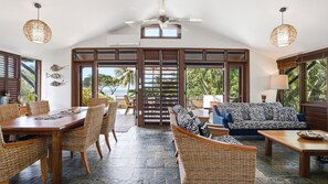 Amplia sala de estar con mesa de comedor, mobiliario de mimbre y vistas al exterior.