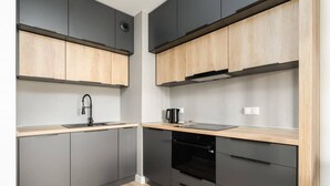 Une cuisine moderne avec des meubles gris, des plans de travail en bois et un four noir.