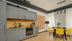 Une cuisine moderne avec des armoires grises, un plan de travail en bois et un mur d’accent en briques.