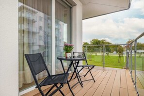 A balcony with two black chairs, a small round table, and a potted plant.