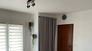 A living room with a grey sofa, a wooden door, and a window with blinds.