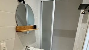 A bathroom with a sink, mirror, and shower.