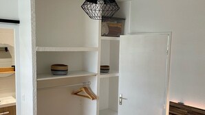 A room with a bed, a wardrobe, a hanging rack, and a ceiling light fixture.