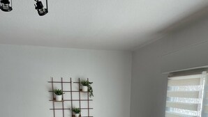 A dining area with a wooden table and chairs, a white refrigerator, and a wall-mounted plant shelf.