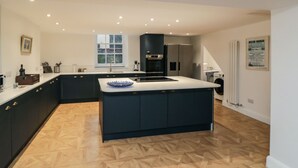 A modern kitchen with dark cabinetry, a central island, and a built-in oven.