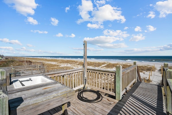 A wooden deck with a view of the beach and ocean.