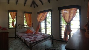 Une chambre à coucher avec un lit, des rideaux, une petite table et une fenêtre donnant sur un paysage verdoyant.