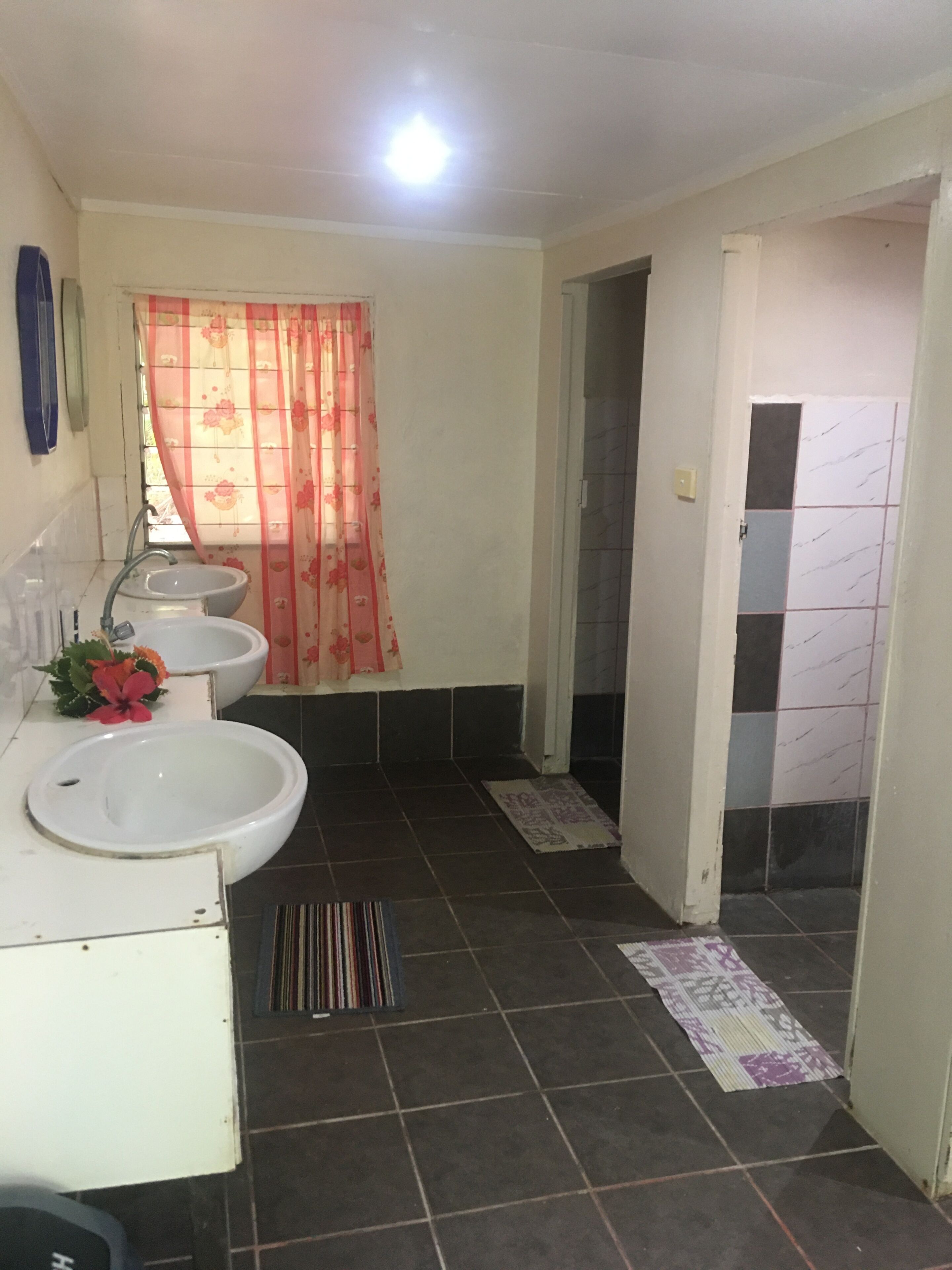 A bathroom with two sinks, a shower curtain, and a tiled floor.