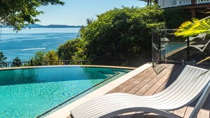 Ein Pool mit klarem, blauem Wasser, einer Holzterrasse und einer Liege.