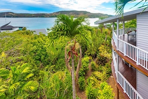 A house with a balcony overlooking a lush garden and a lake.