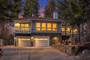 A two-story house with a stone facade, a balcony, and a garage.