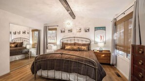 Un dormitorio con una cama de estructura metálica, una mesita de noche, una lámpara y un aparador.