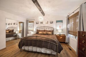 A bedroom with a metal-framed bed, a bedside table, a lamp, and a dresser.