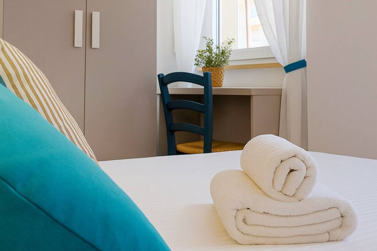 A bedroom with a bed, a desk, a chair, and a wardrobe.