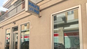 A building with a sign reading "PIANETA BICI" and a large window displaying bicycles.