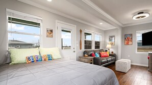 Quarto com cama grande, sofá, abajur e televisão.