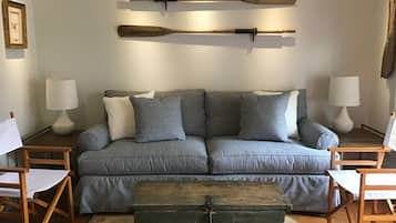 Relax in this inviting living space with a comfortable sofa, wooden coffee table, and unique wall decor.
