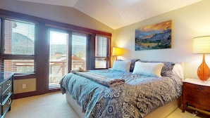 Een slaapkamer met een groot bed, een nachtkastje, een dressoir en een schilderij aan de muur.