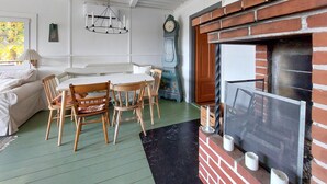 A cozy dining area with a brick fireplace, a table with chairs, and a vintage clock. - 3 bedroom awesome home in örkelljunga (Örkelljunga)