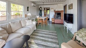 A cozy living room with a sofa, a dining table with chairs, a fireplace, and a television. - 3 bedroom awesome home in örkelljunga (Örkelljunga)