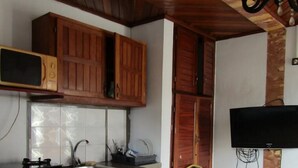 Una cocina con armarios de madera, un microondas, una estufa a gas, un fregadero y un televisor de pantalla plana montado en la pared.