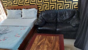 Una habitación con una cama, un sofá de cuero negro y una mesa de centro de madera.