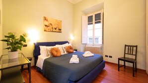 Une chambre à coucher bien rangée, avec un lit, une table de chevet, une chaise et une plante en pot.