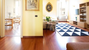 Un salon avec un plancher en bois, un canapé, une table basse et un tapis à motifs.